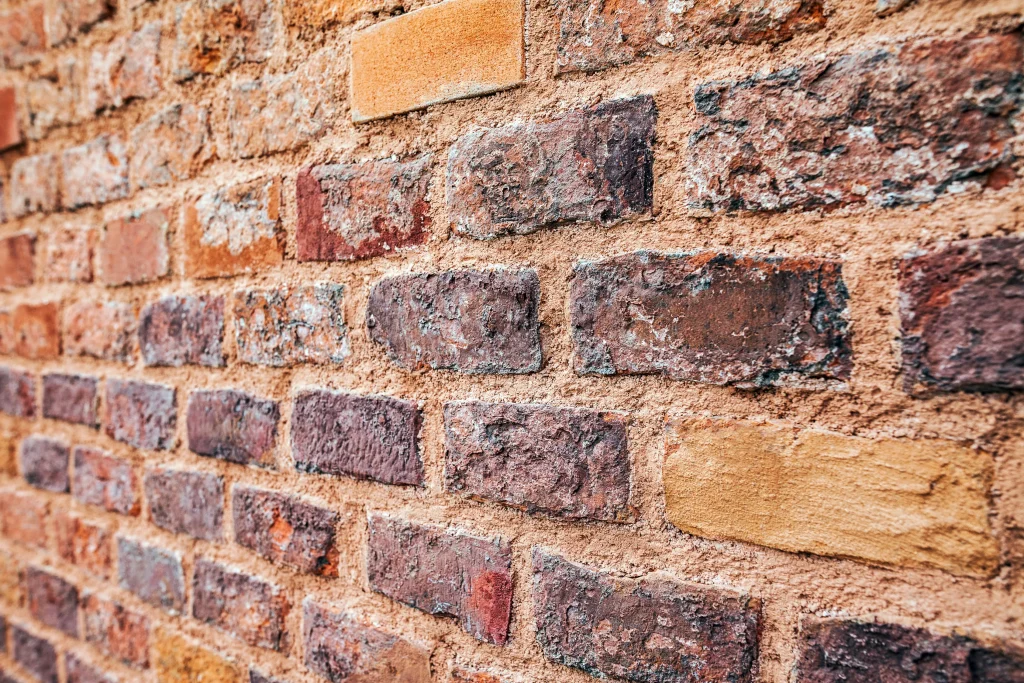 Close-up of a textured brick wall with varying shades of red and brown. The aged surface conveys a rustic and historic ambiance.